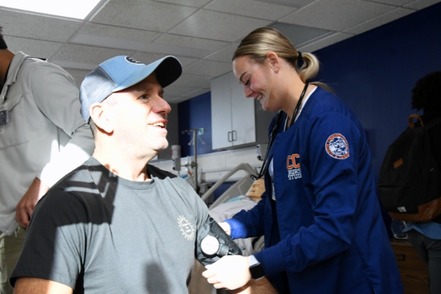 A person getting his blood pressure checked by a Clinton Community College student in a lab setting