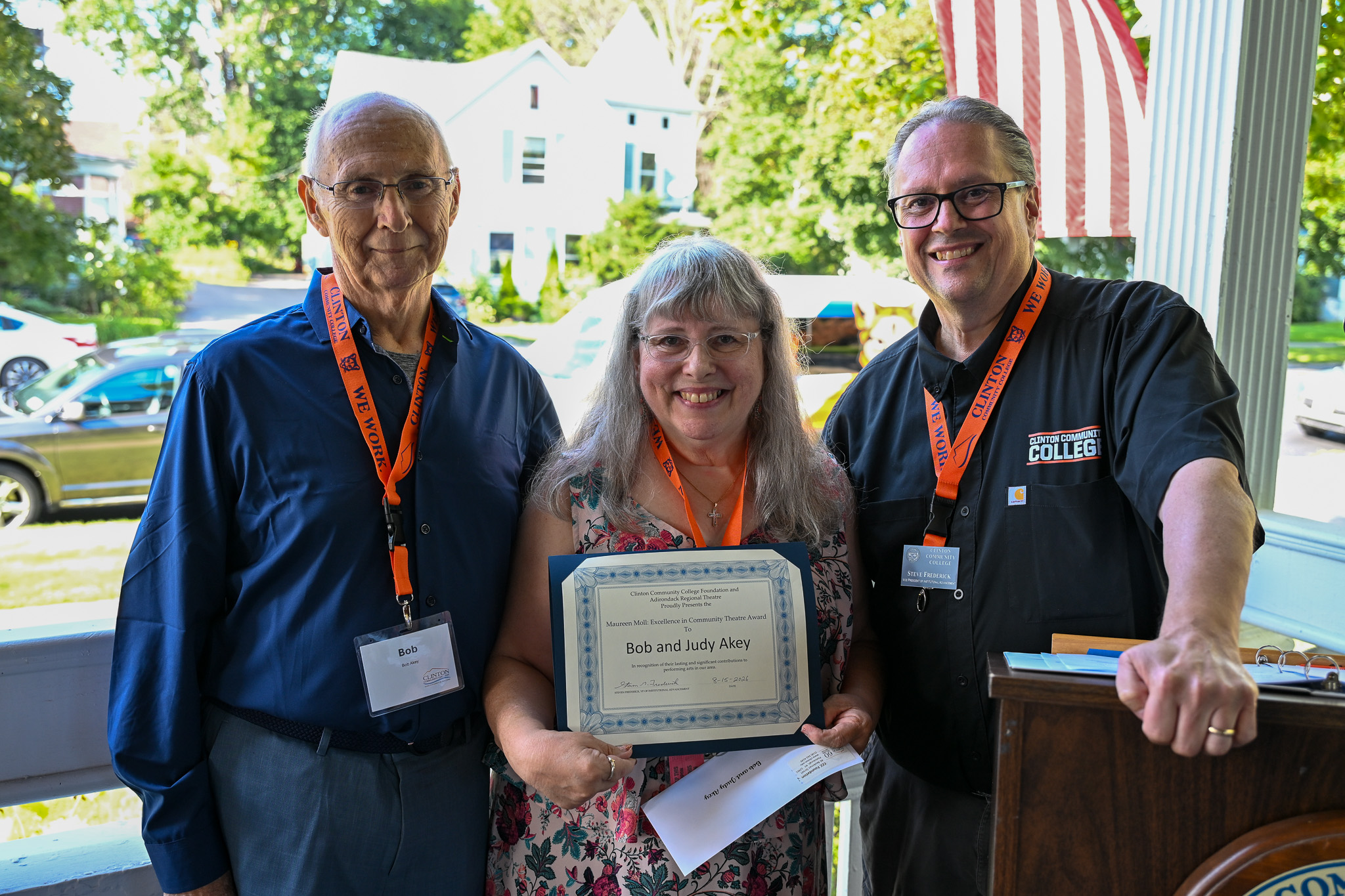 Three people standing next to each other with one person holding an award