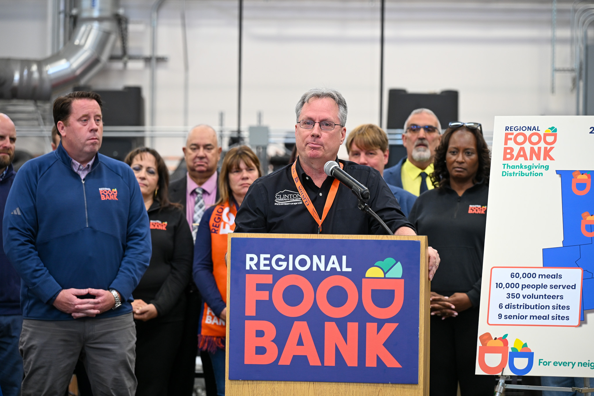 A man speaking at a podium with people standing behind him