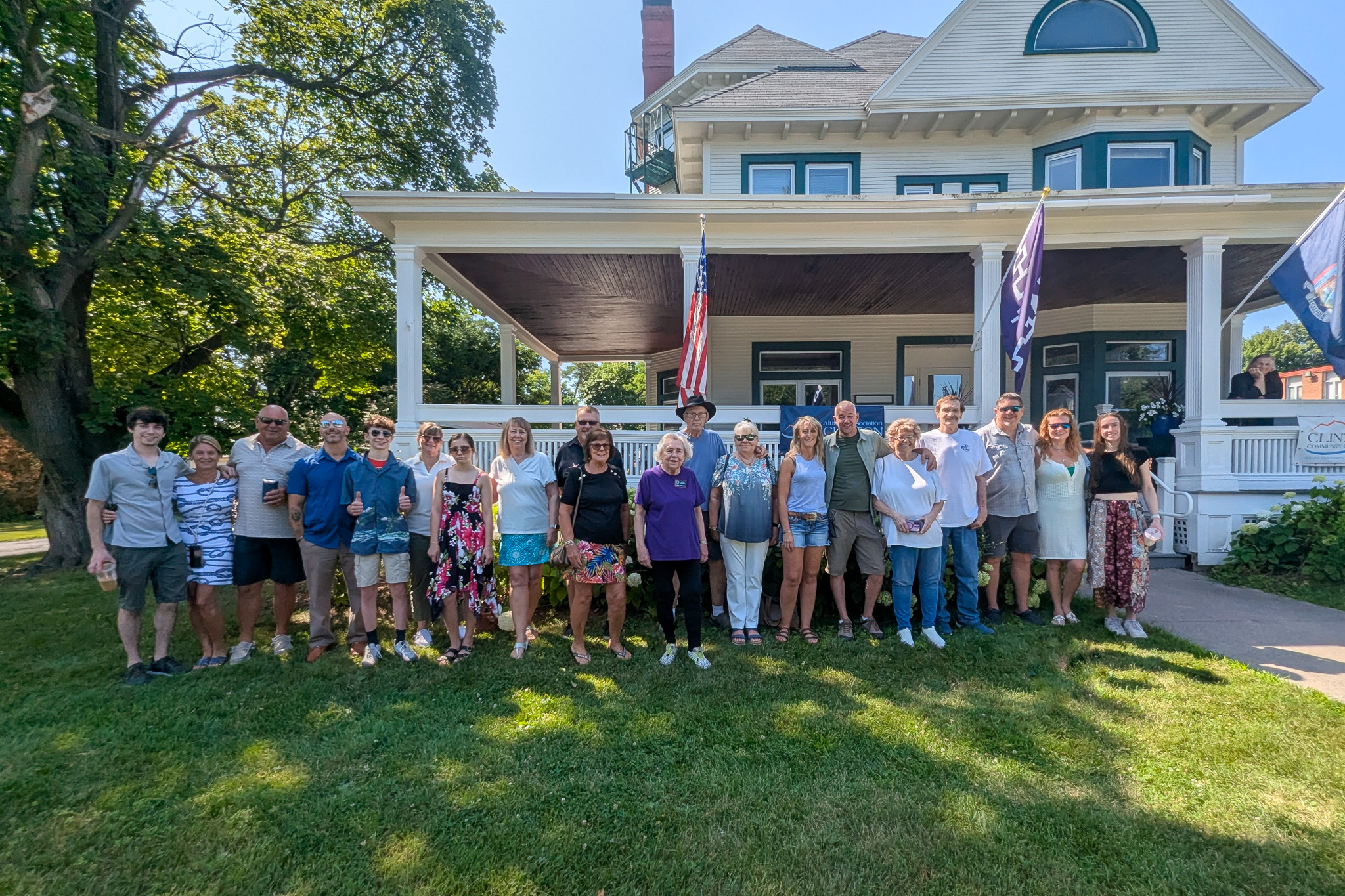 More than a dozen people standing on a lawn in front of a large white house