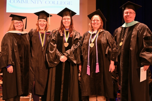 2026 SUNY Chancellor's Excellence Awards Five people posing for a photo on stage wearing graduation regalia