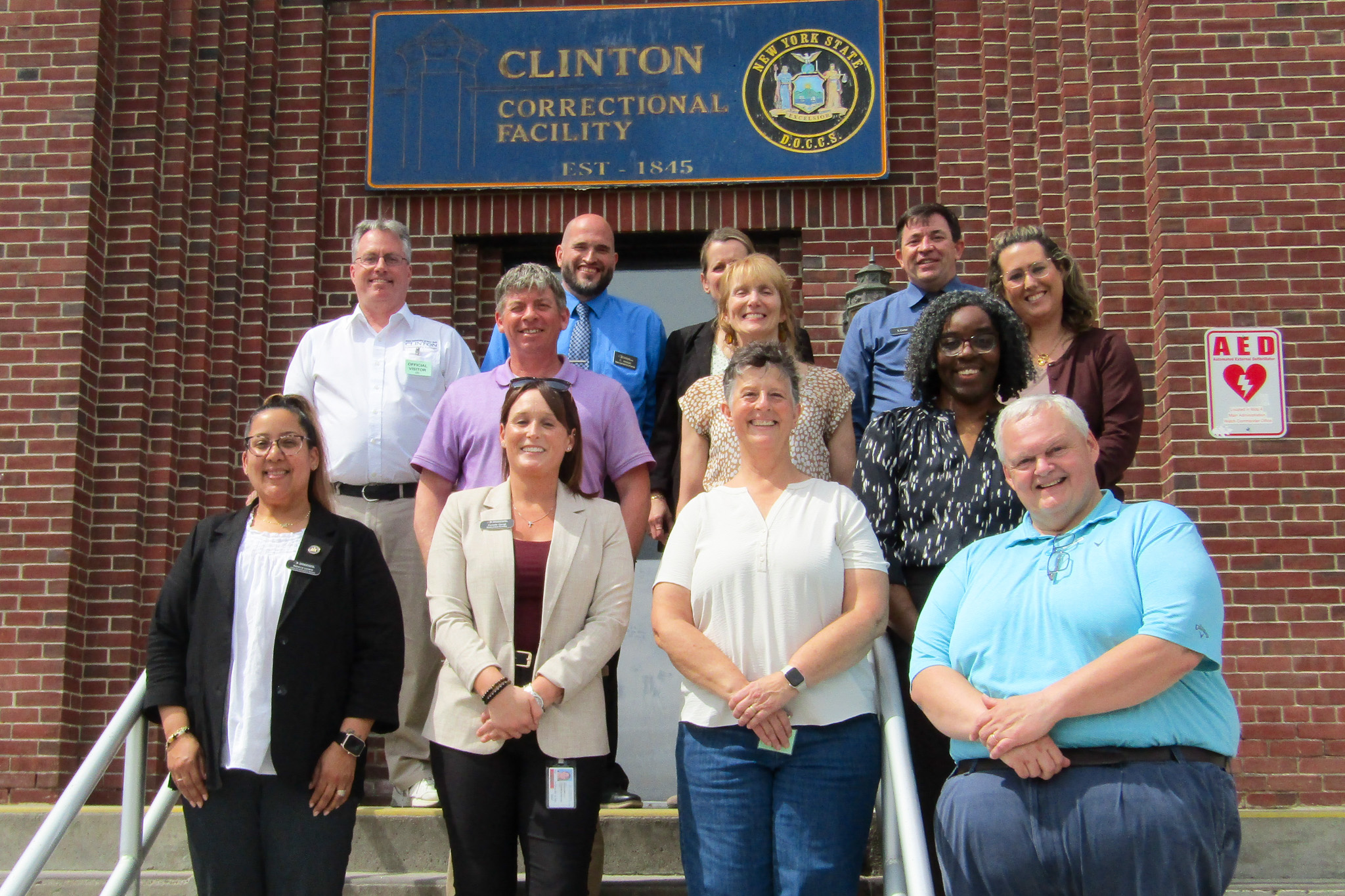 A group of twelve people standing in front of Clinton Correctional Facility