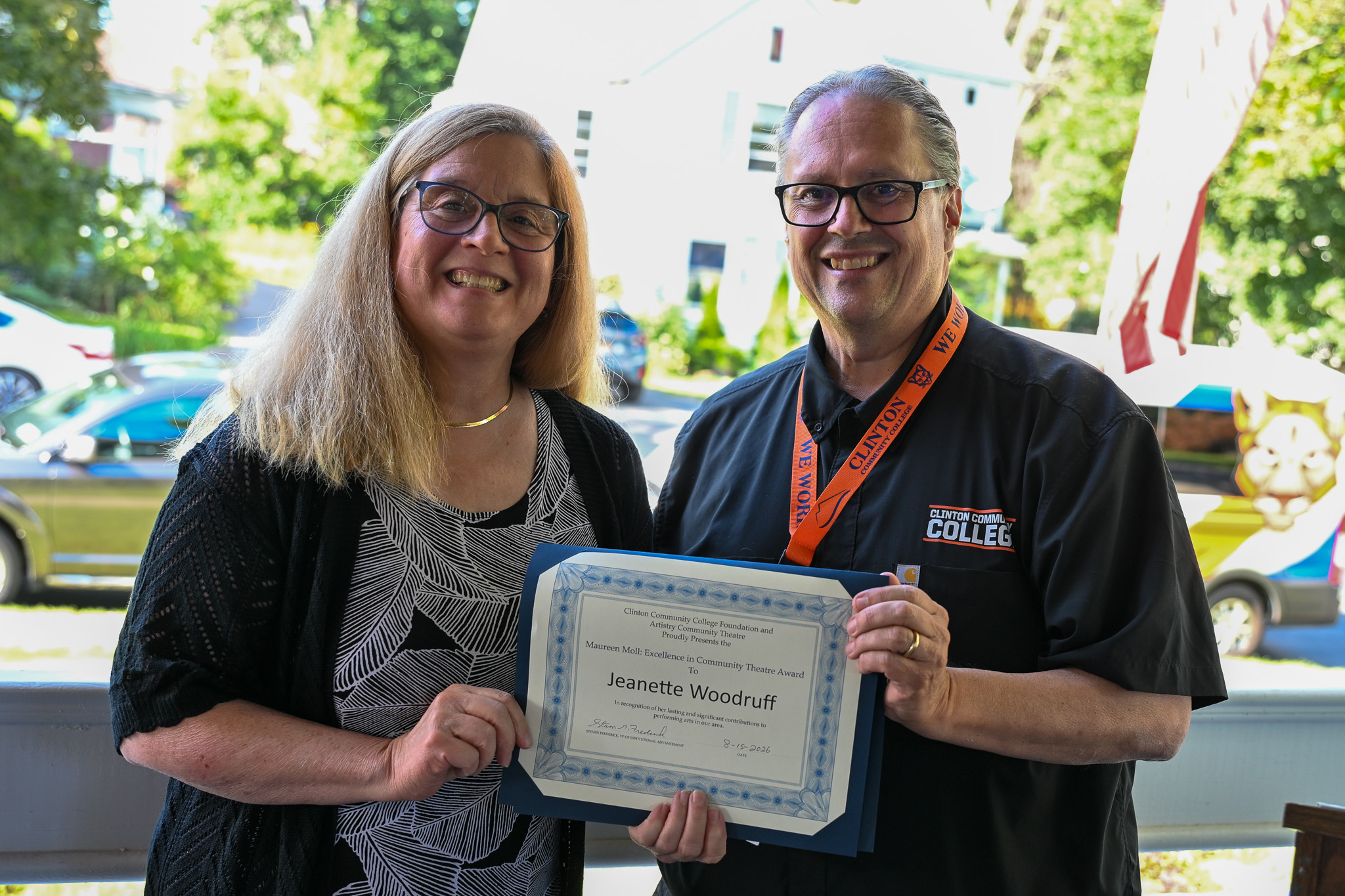 Two people standing next to each other with one person holding an award