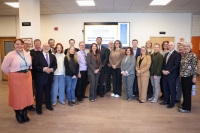A group of people posing together for a photo in front of a TV screen that says 'Clinton Community College' on it