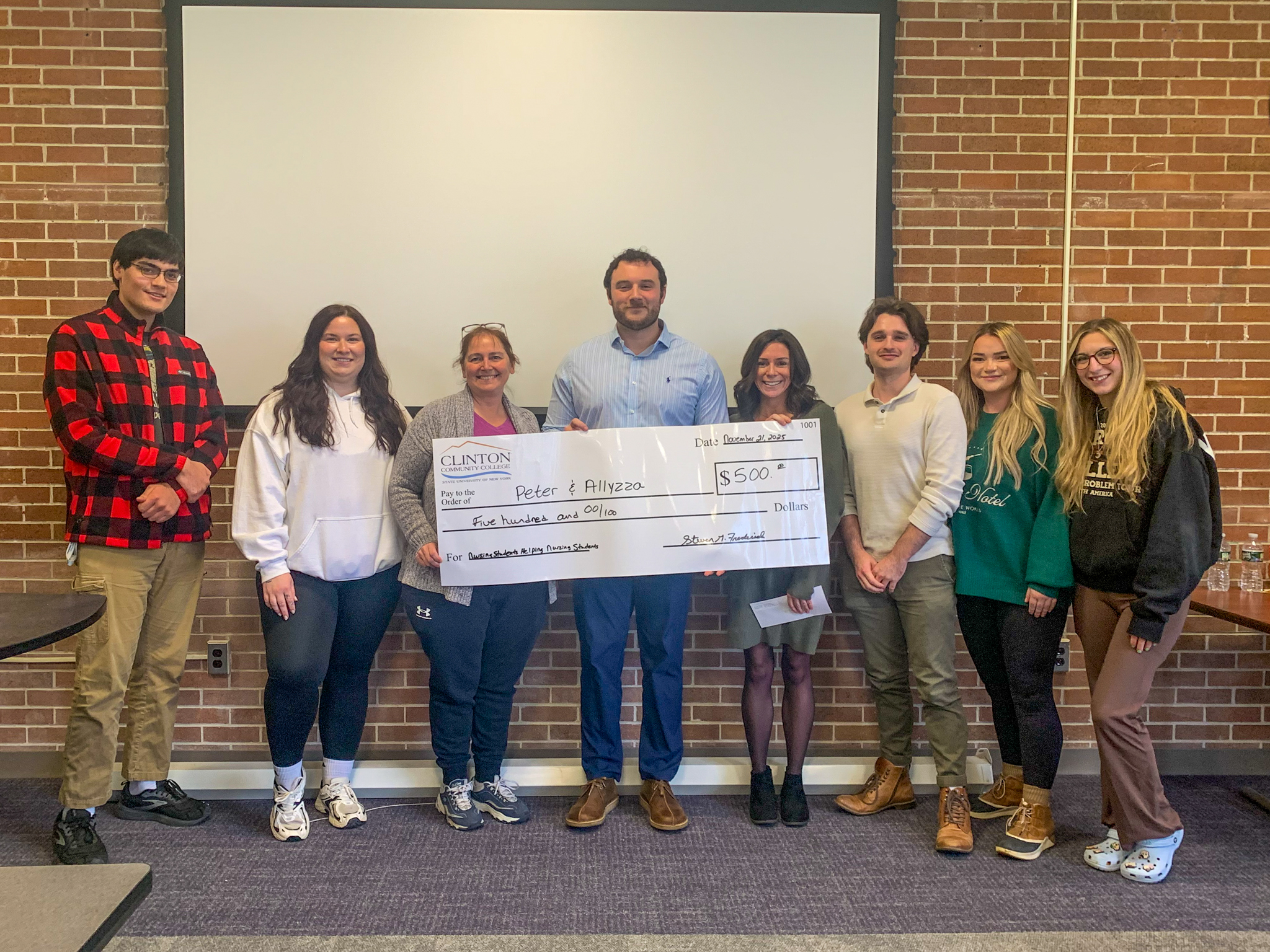 Eight people standing behind an enlarged laminated check at Clinton Community College