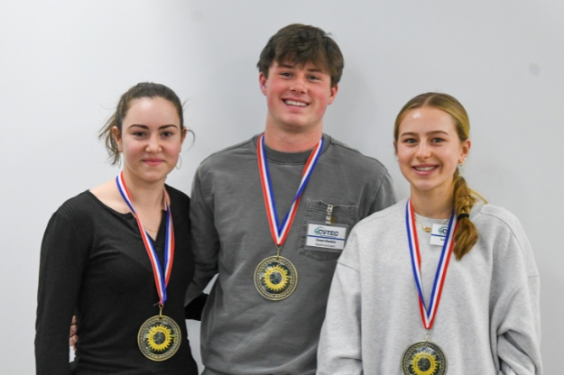 Three students standing side-by-side with medals around their necks