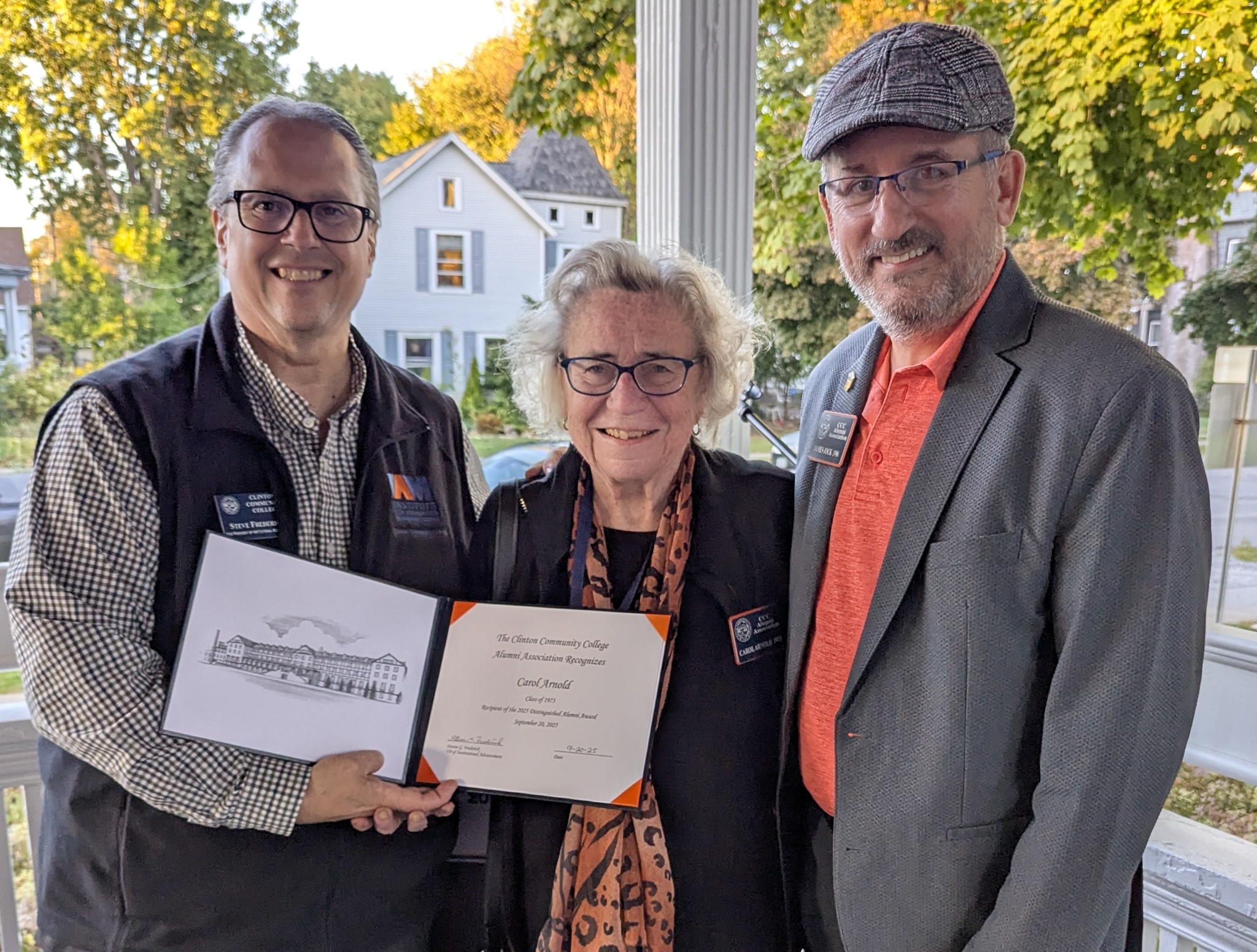 A man holds up a certificate next to a woman and a man