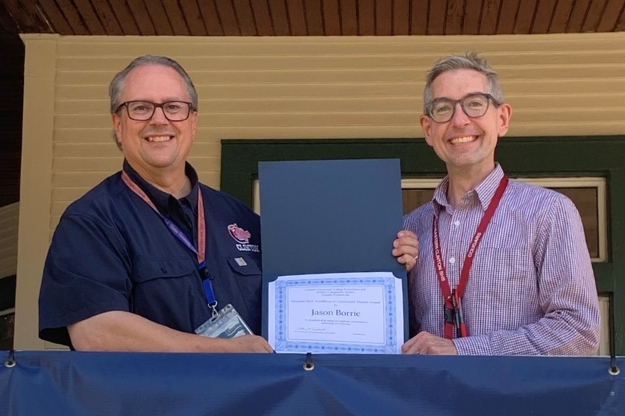 Two people standing side by side with one person holding up a certificate