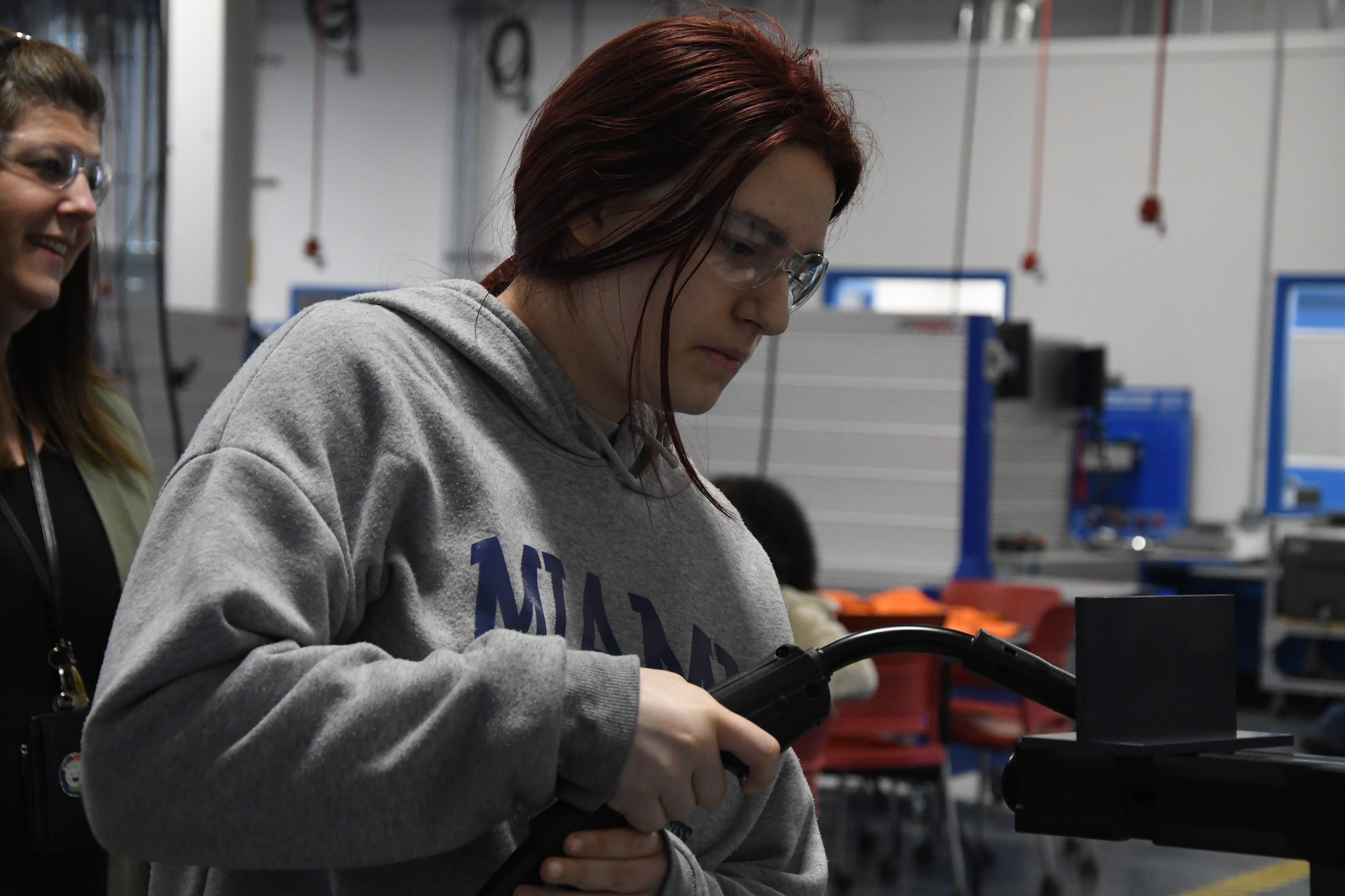 Female student using welding simulation machine.