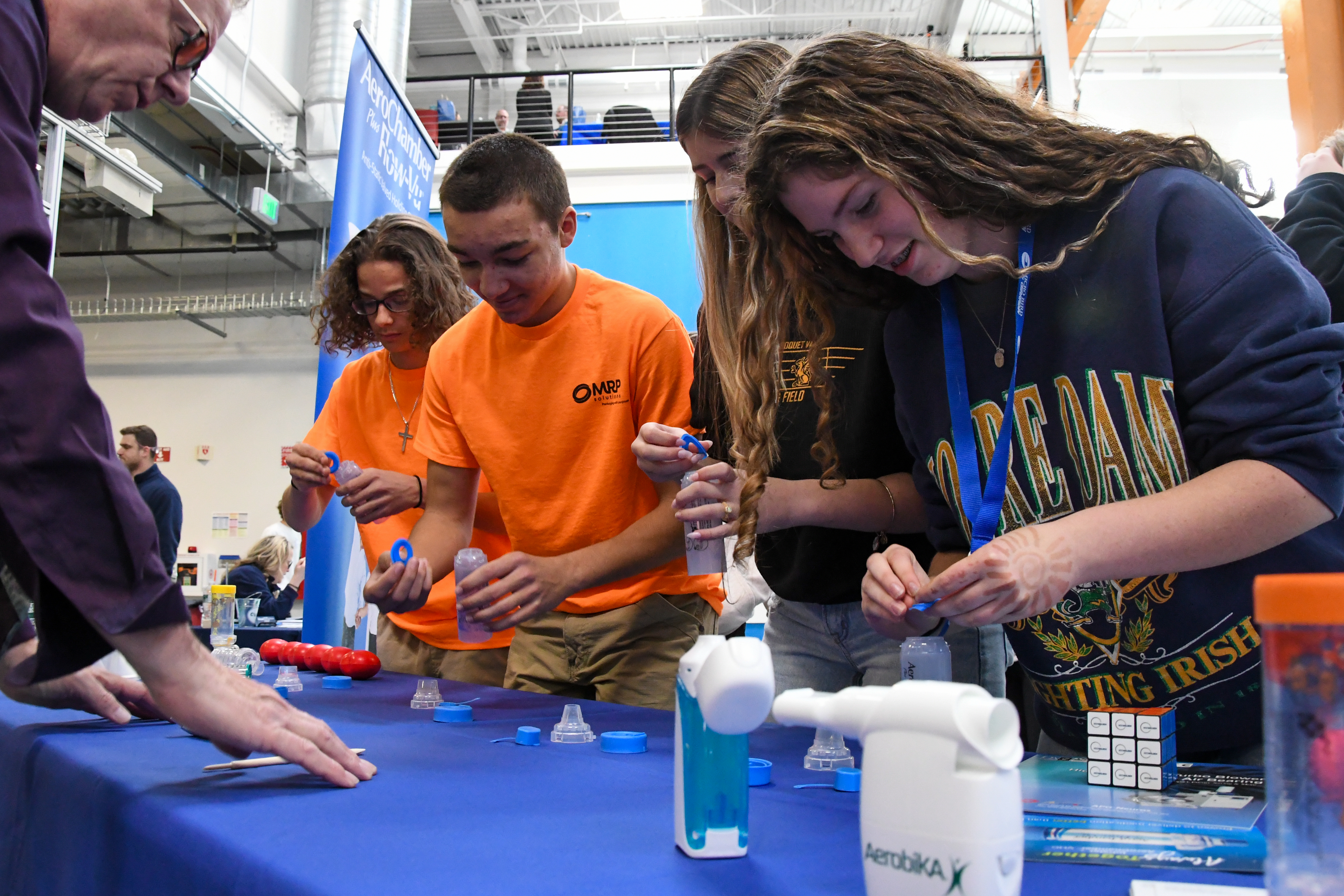 Four students working on assembling an item in front of a vendor