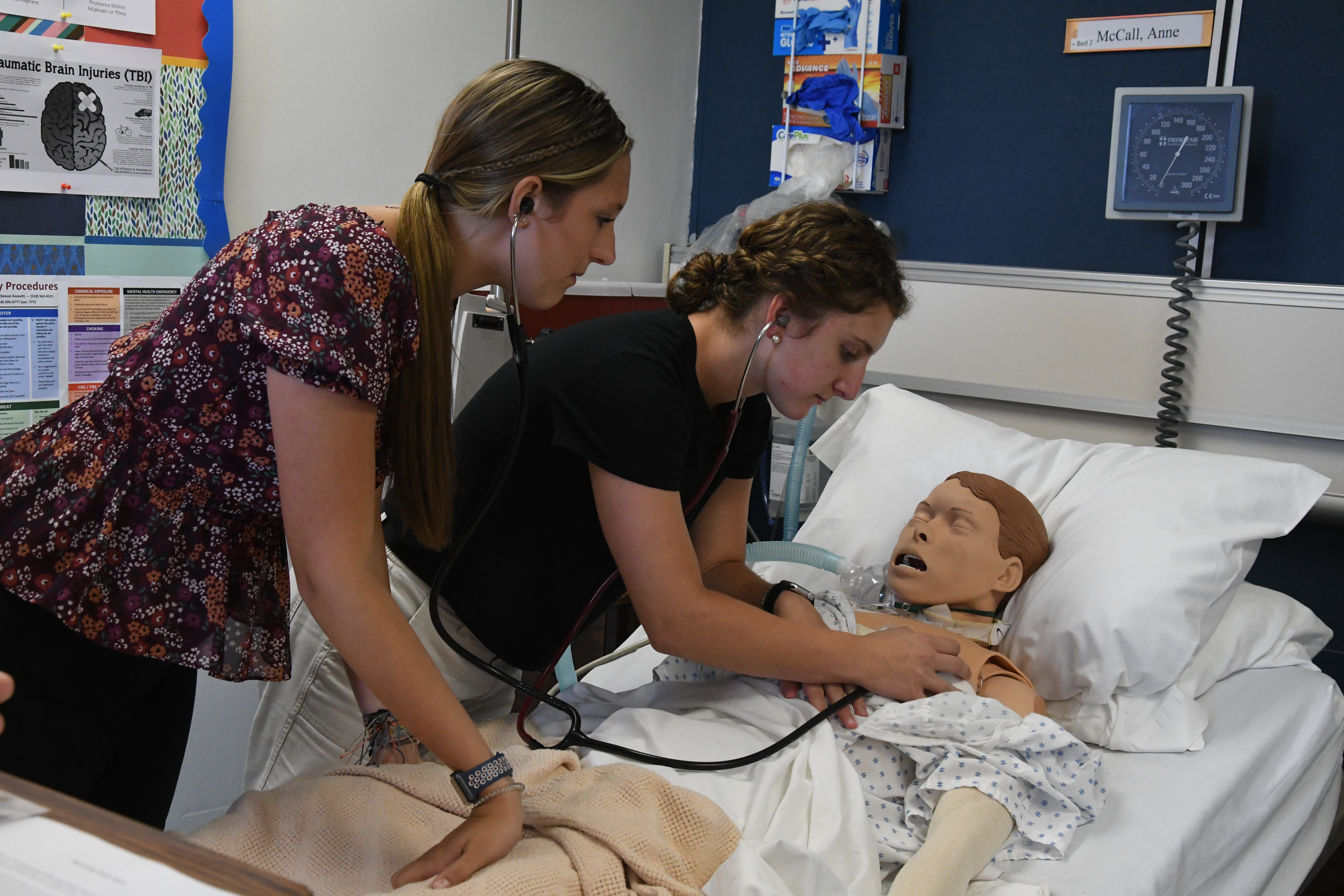 2 students listening to a mannequin's heartbeat